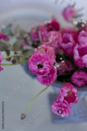 Pink ranunculus and pink tulips arranged in iron vase