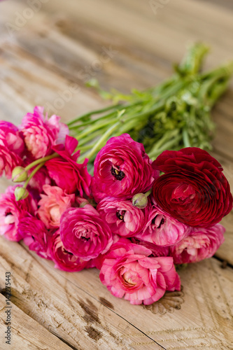 Bouquet of pink ranunculus lying on rustic tabletop