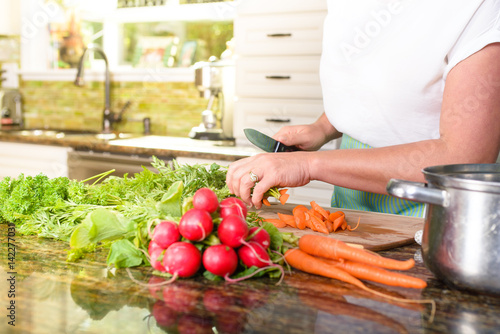 Close-up of woman cutting vegetables in sunny kitchen