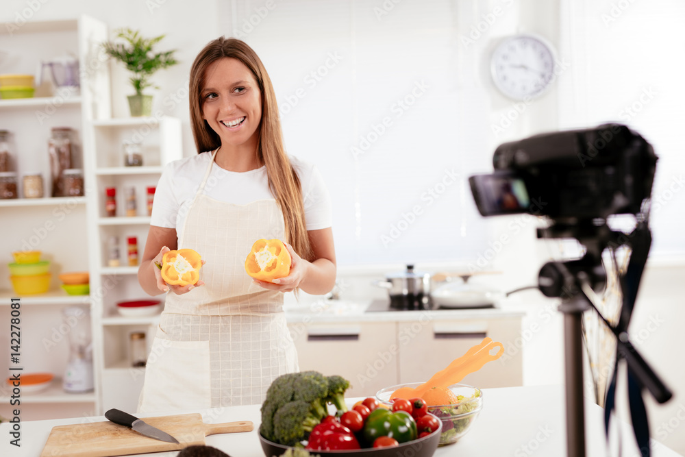Attractive Blogger Girl filming her blog broadcast about healthy food at the home.