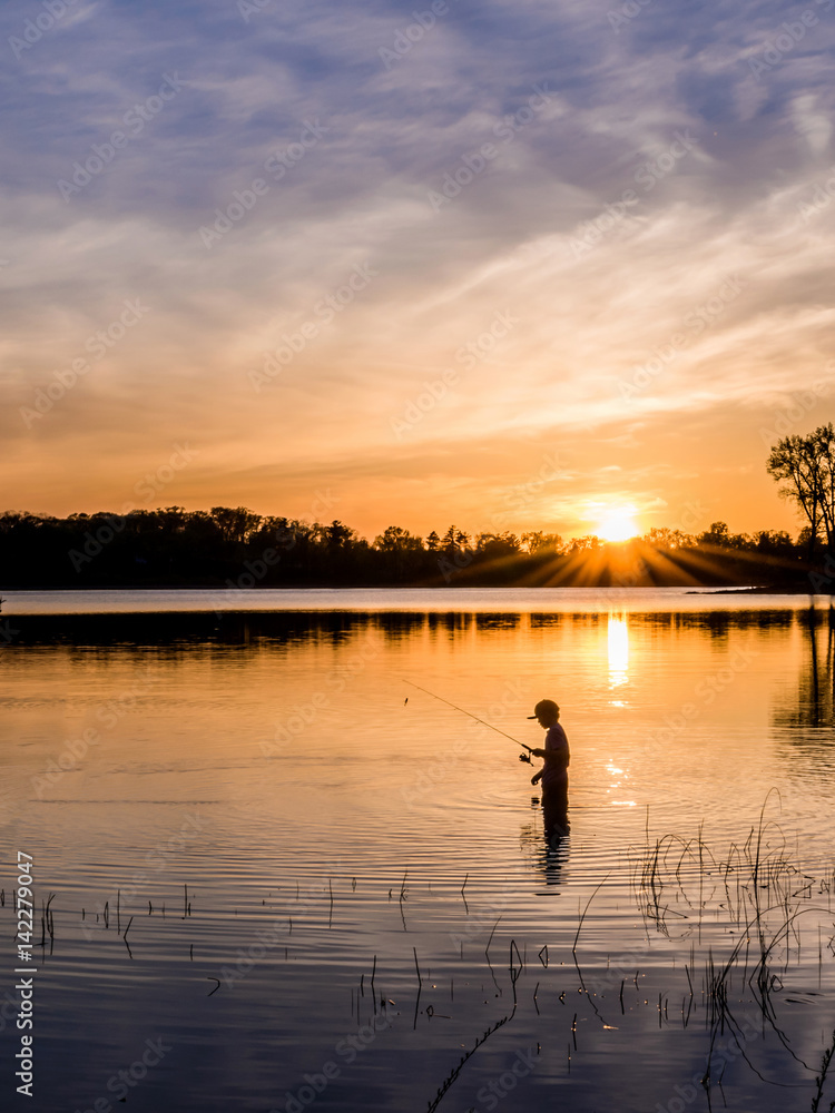 Two young kids are fishing under sunset of a lake Two young kids are fishing under sunset of a lake