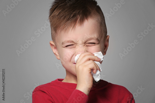 Cute little boy sneezing in...