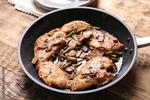 Frying pan with delicious chicken marsala on table