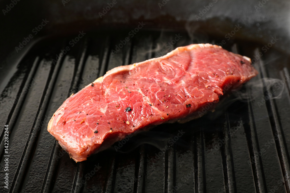 Preparing of steak on grill pan, closeup