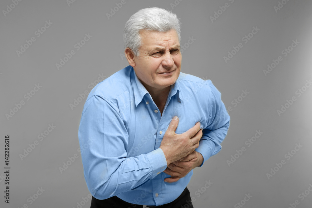 Man with chest pain suffering from heart attack on grey background Man with chest pain suffering from heart attack on grey background