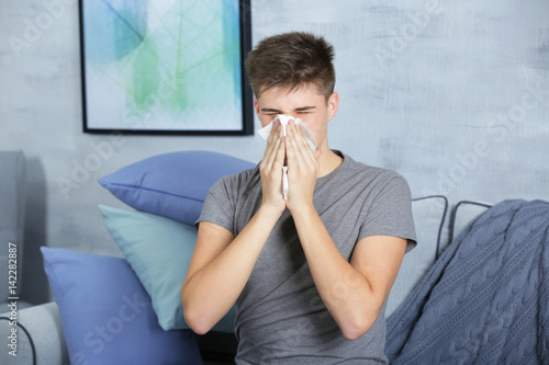 Young man blowing nose on t...