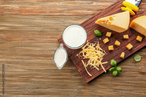 Cutting board with cheese on wooden background