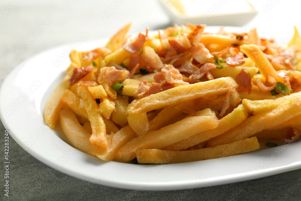 Portion of delicious french fries with bacon and onion, closeup Portion of delicious french fries with bacon and onion, closeup