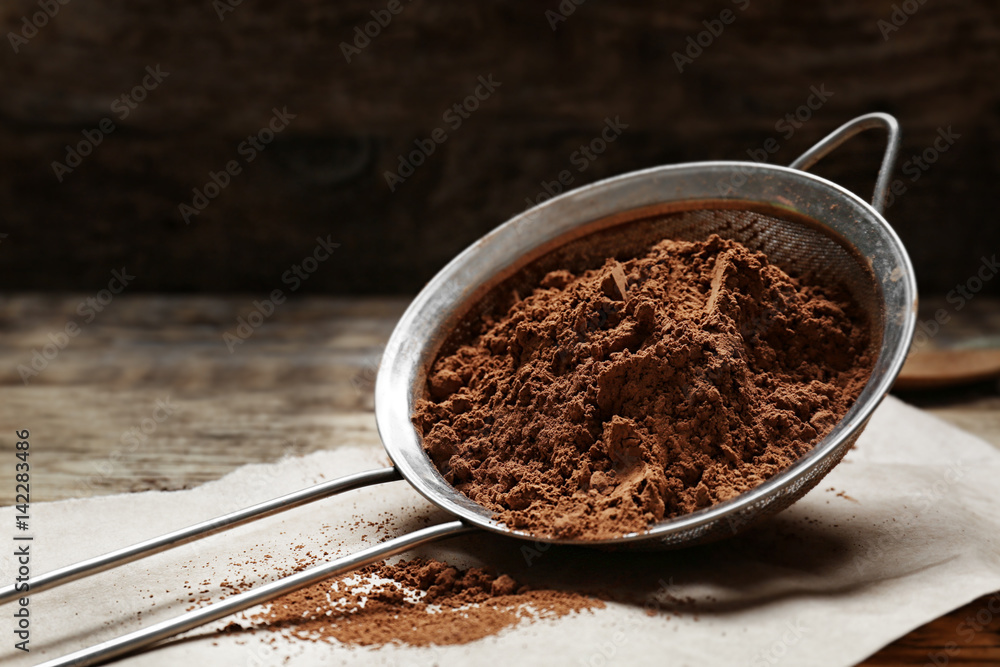 Metal sieve with cocoa powder on kitchen table Metal sieve with cocoa powder on kitchen table