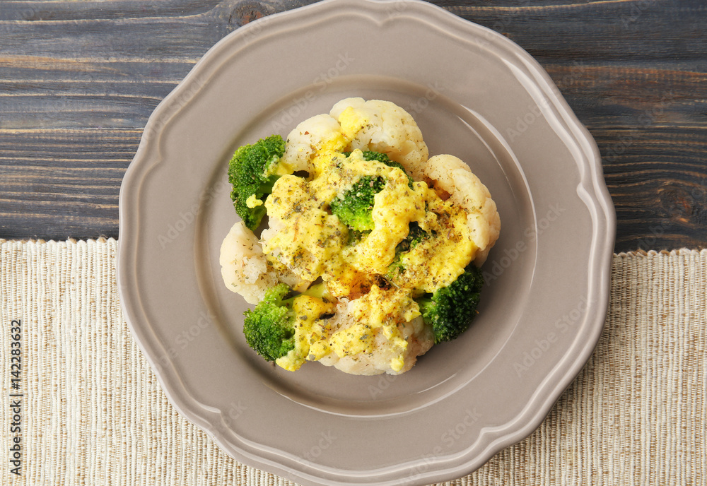 Delicious cauliflower and broccoli with cheese sauce on grey plate