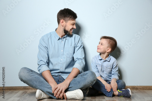 Father and his son sitting on floor near color wall