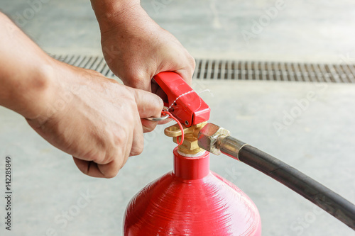 Foto Male hands pulling safety pin of fire extinguisher closeup