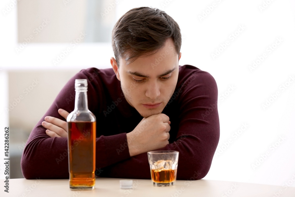 Handsome depressed man drinking whisky at home Handsome depressed man drinking whisky at home
