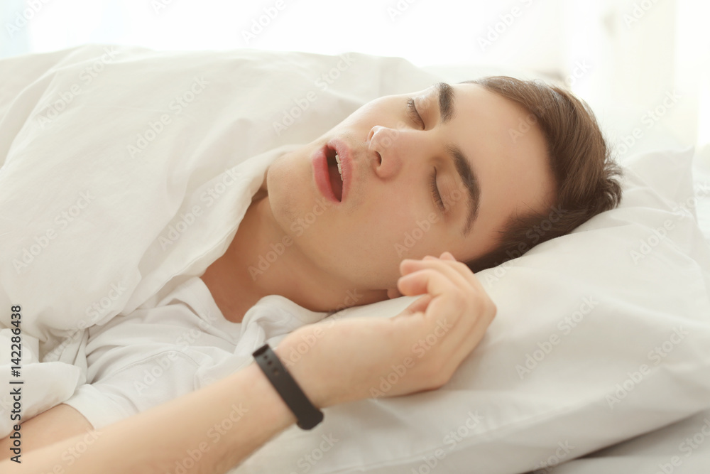 Young man with sleep tracker resting in bed at home Young man with sleep tracker resting in bed at home