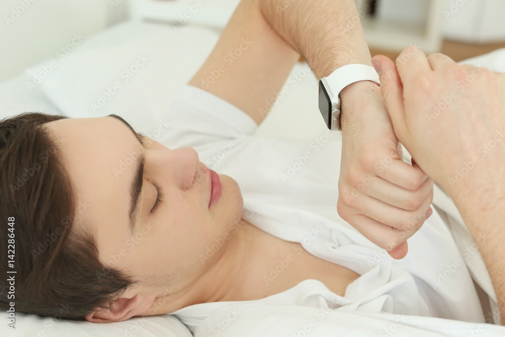 Young man with sleep tracker lying in bed at home, closeup Young man with sleep tracker lying in bed at home, closeup