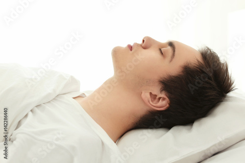 Tired young man sleeping in bed at home