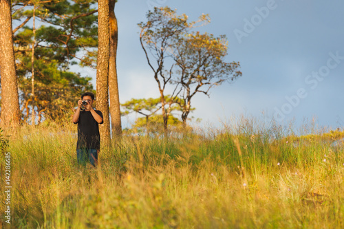 Man taking photos of landscape in the forest at Phu Soi Dao, Uttaradit, Thailand. © Korradol