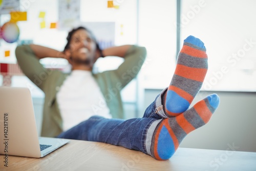 Male graphic designer relaxing with feet up at desk photo