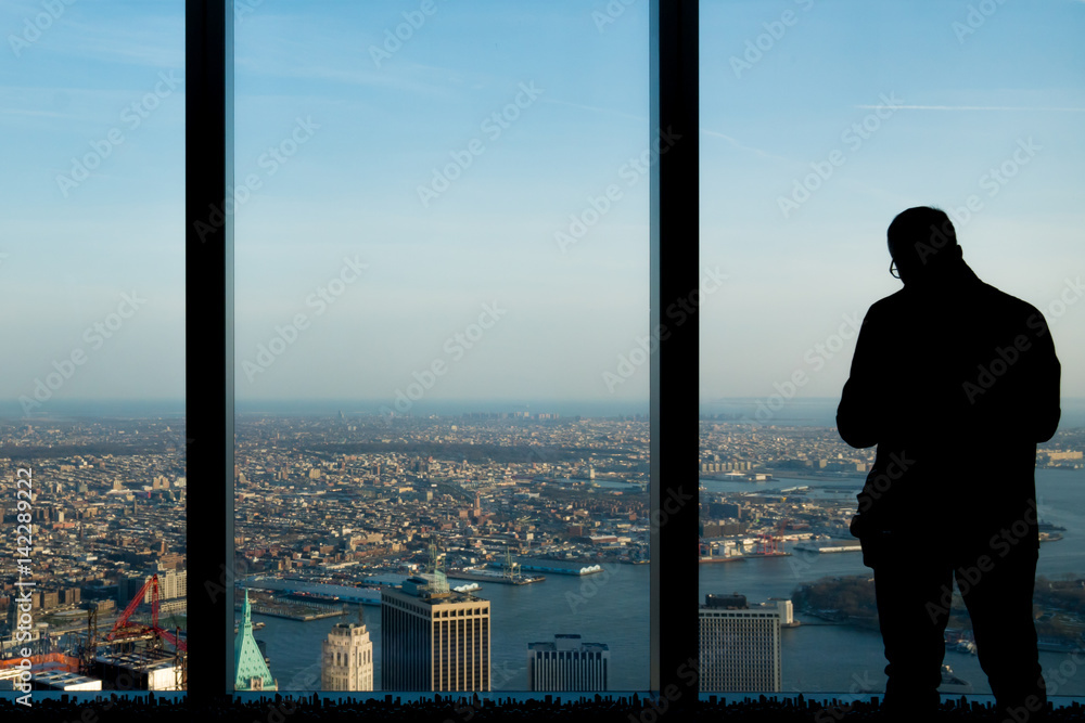Man with glasses looking out office tower window Man with glasses looking out office tower window