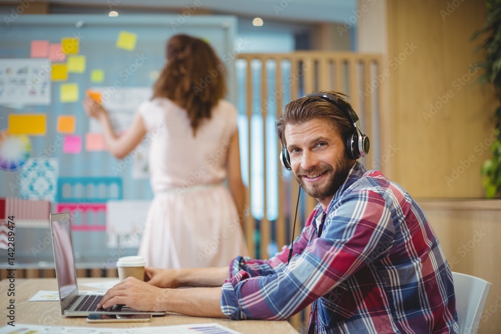 © WavebreakMediaMicro - Portrait of business executive listening song while using laptop