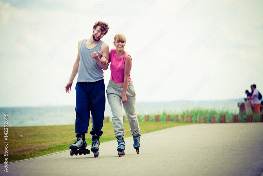 Young couple holding hands while rollerblading Young couple holding hands while rollerblading