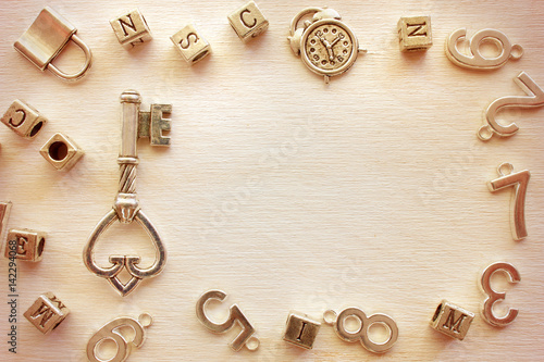 Old vintage metal key in frame from different metal letters and numbers with copy space