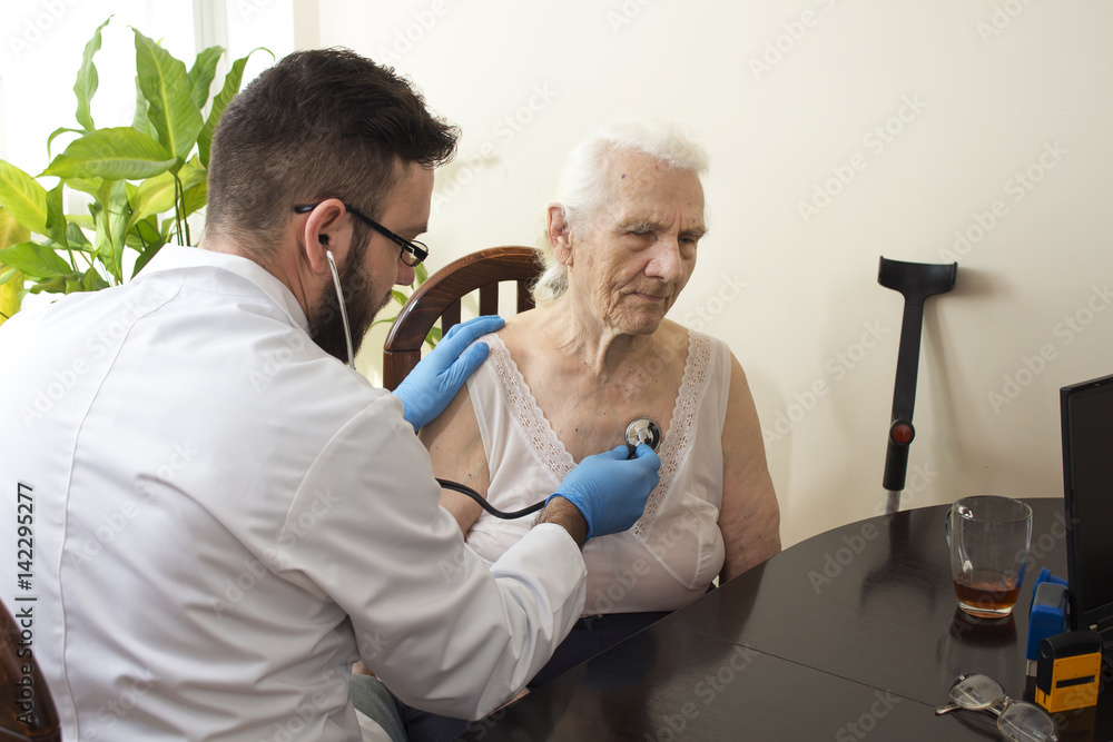 Lekarz bada stetoskopem starą kobietę w gabinecie lekarskim. Badanie lekarskie stetoskopem. Lekarz geriatra bada płuca. - obrazy, fototapety, plakaty 