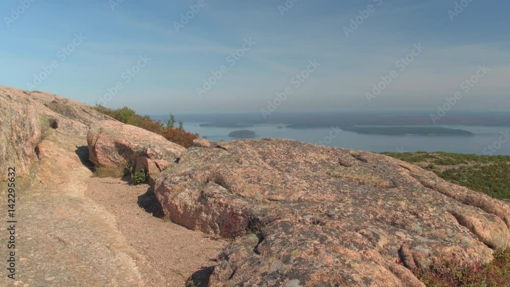 CLOSE UP: Granite rocks on the top of the Mount Desert Island surrounded by low vegetation, lush fall foliage shrubs and young spruce trees overlooking North Atlantic Ocean shore on sunny autumn day CLOSE UP: Granite rocks on the top of the Mount Desert Island surrounded by low vegetation, lush fall foliage shrubs and young spruce trees overlooking North Atlantic Ocean shore on sunny autumn day