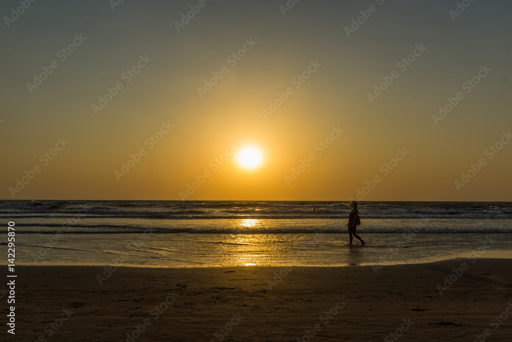 Woman are walking at sunseton Arambol beach, Goa, India
