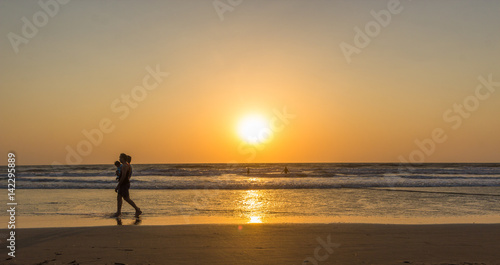 Woman are walking at sunseton Arambol beach, Goa, India