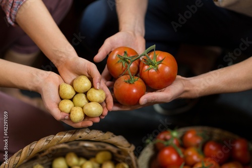 vendors holding tomatoes and potatoes at grocery 