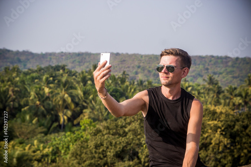 Photography Young man is making a selfie photo from a mobile phone, Goa, India