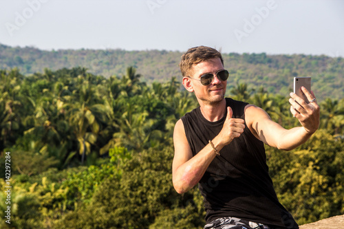 Photography Young man is making a selfie photo from a mobile phone, Goa, India