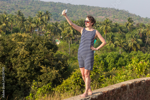 Photography Young woman is making a selfie photo from a mobile phone, Goa, India