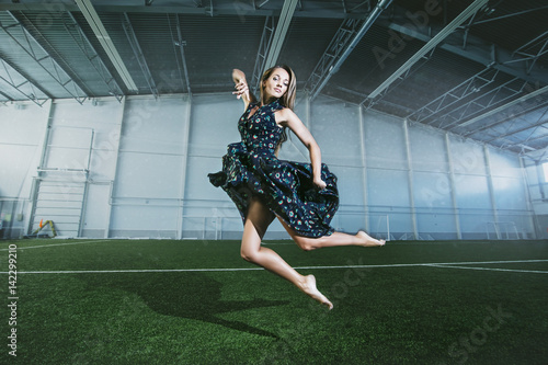 Beautiful young fashion model in a dress at a large sports stadium