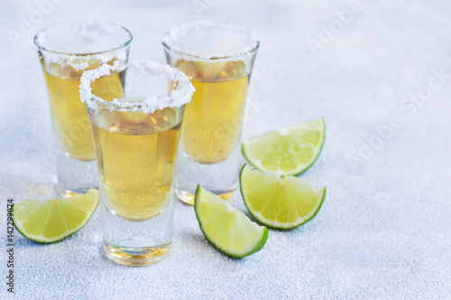 Mexican tequila gold in short glasses with salt and  lime slices, copy space