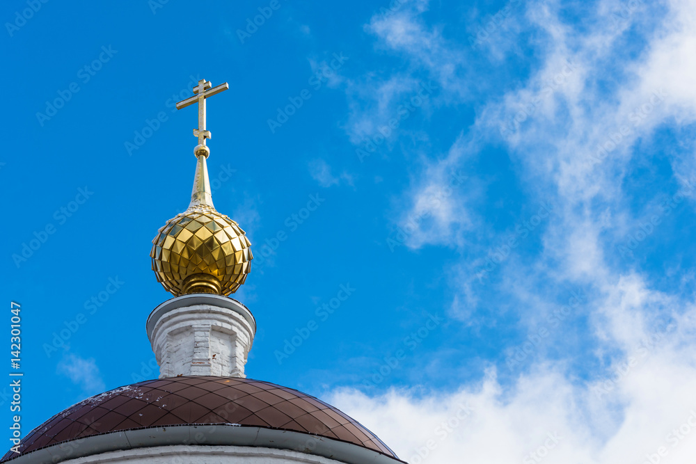 Golden dome with a cross on the sky background.