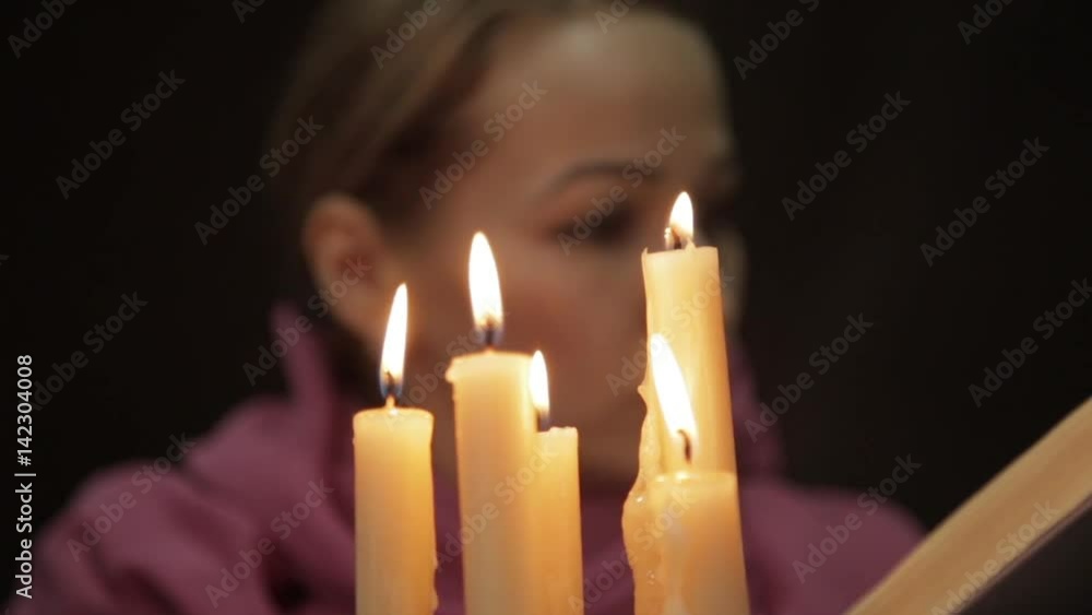 woman in a headscarf doing the magic ritual. close-up several candle and old book. halloween or religion concept woman in a headscarf doing the magic ritual. close-up several candle and old book. halloween or religion concept