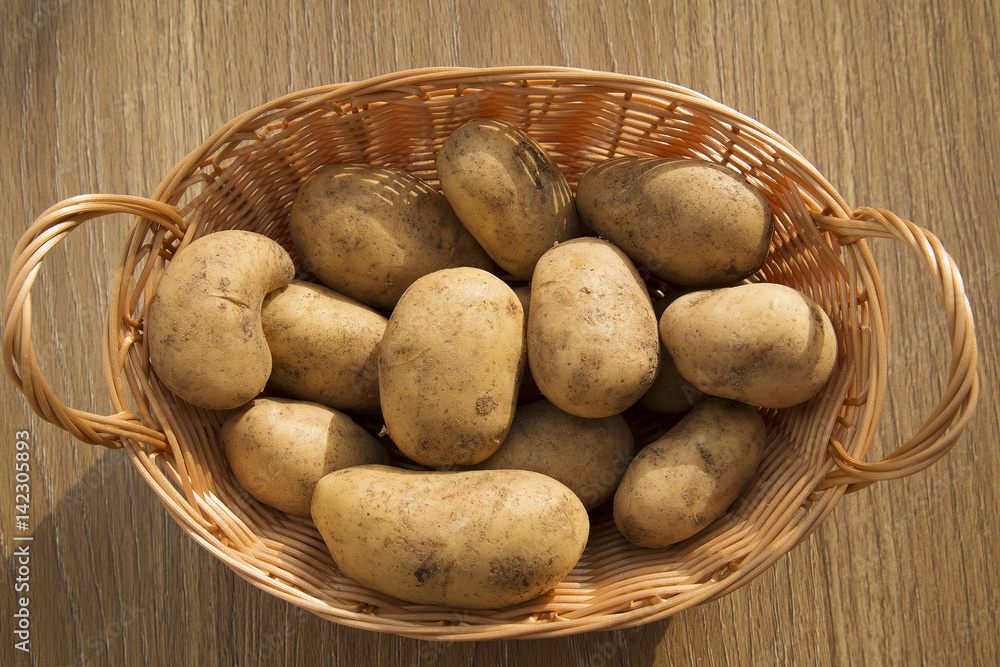 Raw potatoes in a basket on a wooden table Raw potatoes in a basket on a wooden table