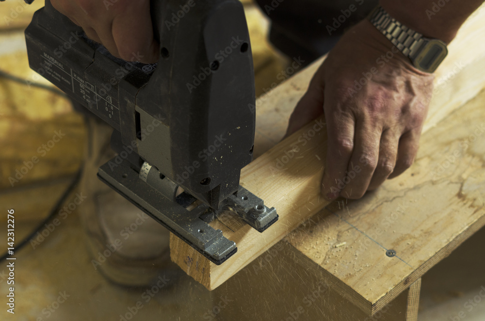 Man cutting wood block with fretsaw at the workshop