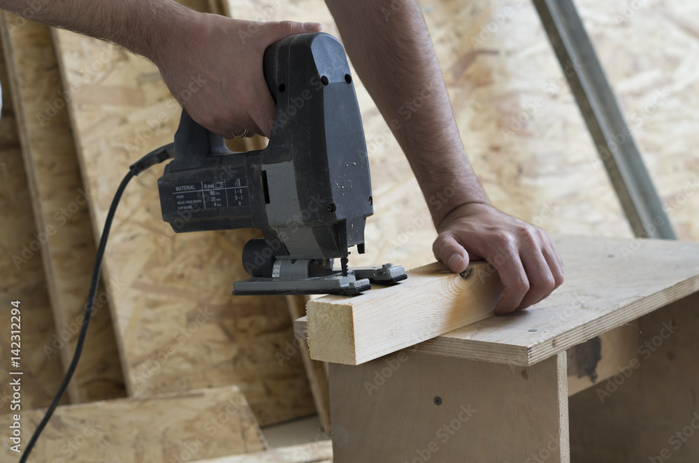 Man cutting wood block with fretsaw at the workshop