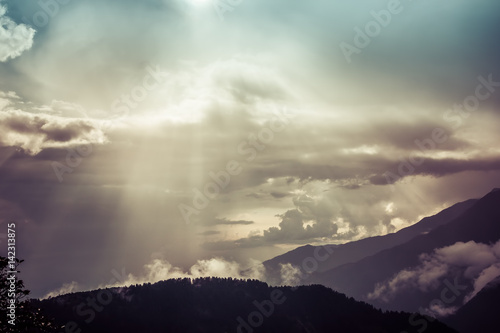 Sun rays protruting through clouds in the mountains