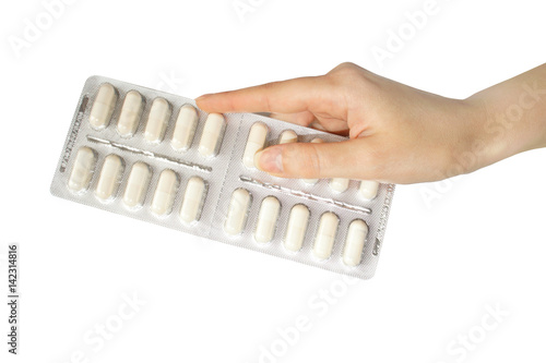 Female hand holding a packet of pills on white background
