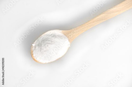 Baking soda in wooden spoon on grey background