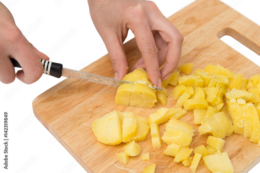 Chef cuts boiled potatoes on board on a white background Chef cuts boiled potatoes on board on a white background