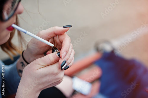 Young girl lighting cigarette outdoors close up. Concept of nicotine addiction by teenagers.