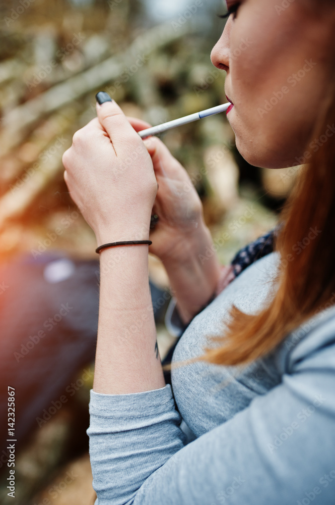 Obraz premium Young girl lighting cigarette outdoors close up. Concept of nicotine addiction by teenagers.