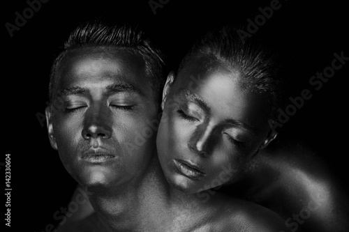 Male and female face around. The woman's head lies on the shoulder of a man. All painted in gold paint, the feeling of a single whole organism. Black and white