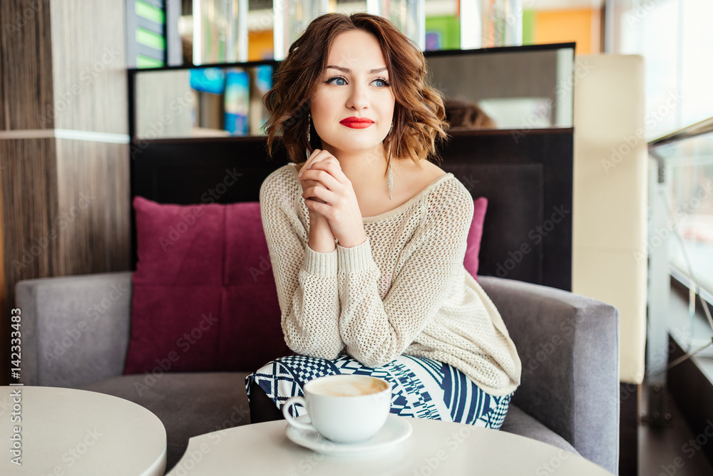 Beautiful cute girl in the cafe near the window with coffee smiling. Fashion model, pretty girl, lips red, make up, close up, beauty street photo Beautiful cute girl in the cafe near the window with coffee smiling. Fashion model, pretty girl, lips red, make up, close up, beauty street photo