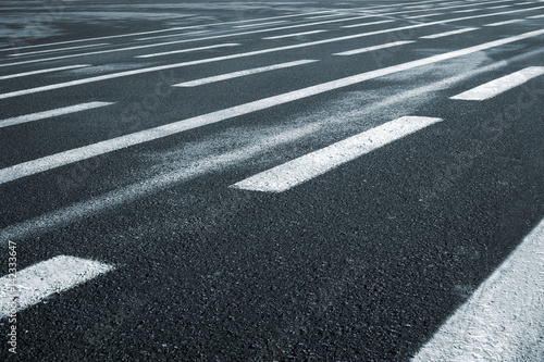 Lines on wet wide asphalt road perspective view.